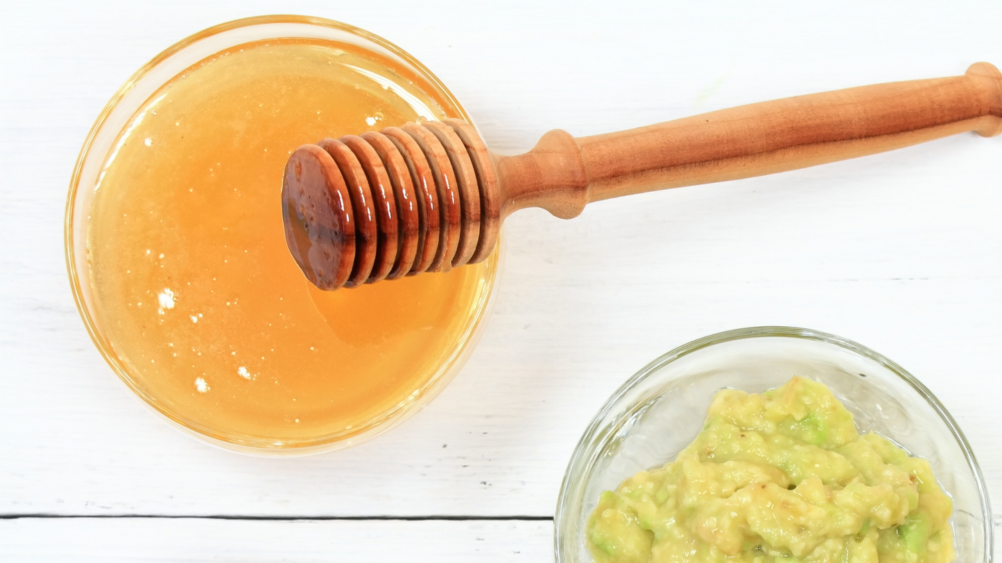 Bowl of honey with honey dipper and a bowl of mashed avocado.