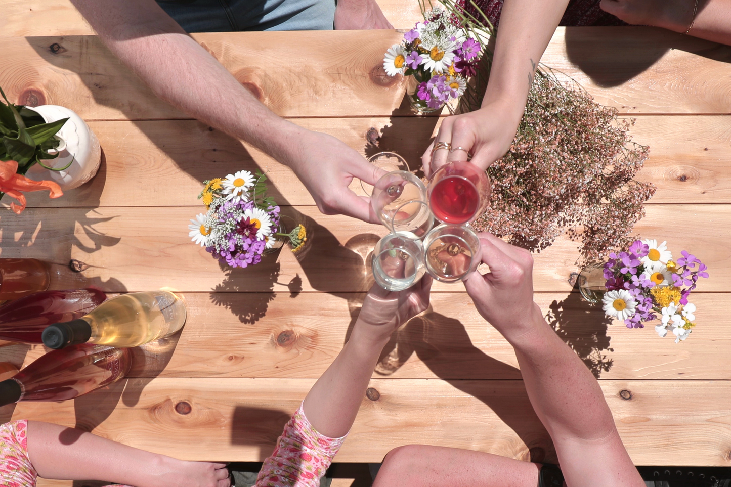 Birds-eye view of four people cheersing mead over a picnic table.