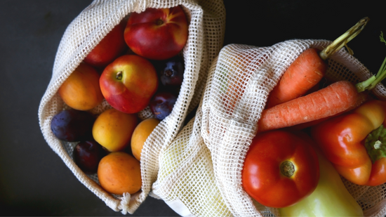 Two cloth produce bags filled with fruit and vegetables. 