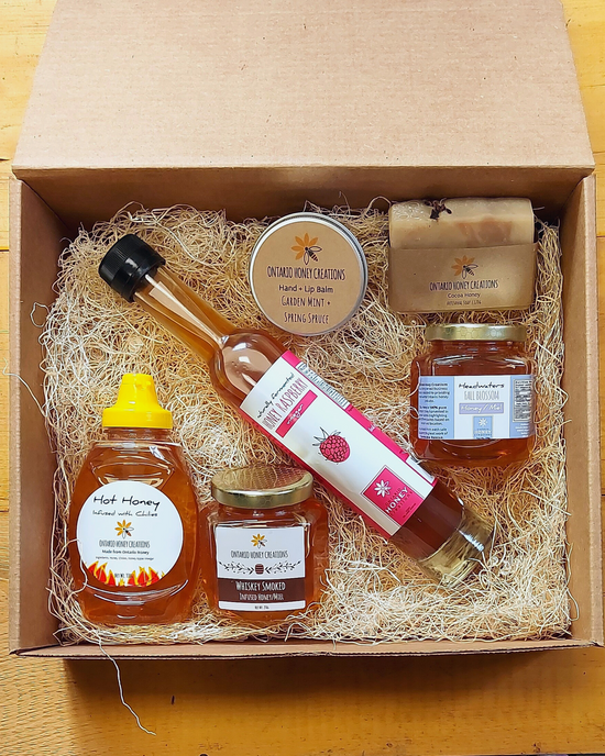 Load image into Gallery viewer, Gift box with Honey Raspberry Vinegar, Hot Honey, Whiskey Smoked Honey, Hand &amp;amp; Lip Balm, and Headwaters Fall Blossom Honey. 
